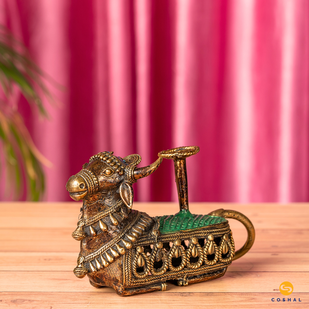 Dhokra Nandi Candle Holder, the sacred bull, is intricately detailed using the ancient Dhokra technique—a method of non-ferrous metal casting practiced for centuries. The result is a stunning candle holder that not only radiates warm, flickering light but also pays homage to Indian heritage.